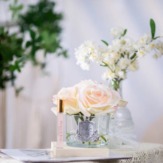 Glass vase with white roses on a table with a blurred background